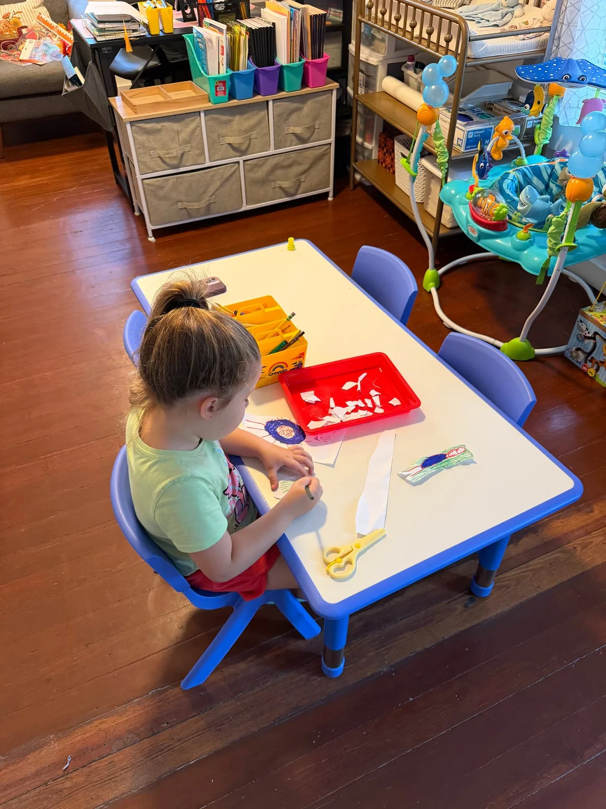 A child drawing and creating artwork at an activity table.